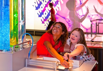 Child with Down’s Syndrome and helper using an interactive exhibit at the Science Museum