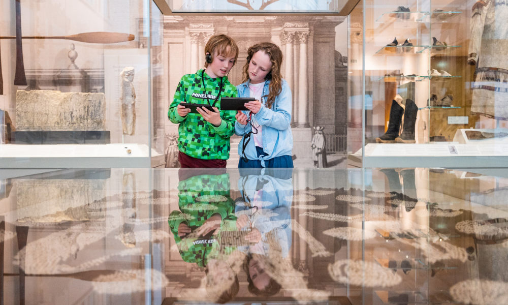 Children use a tablet inside a museum