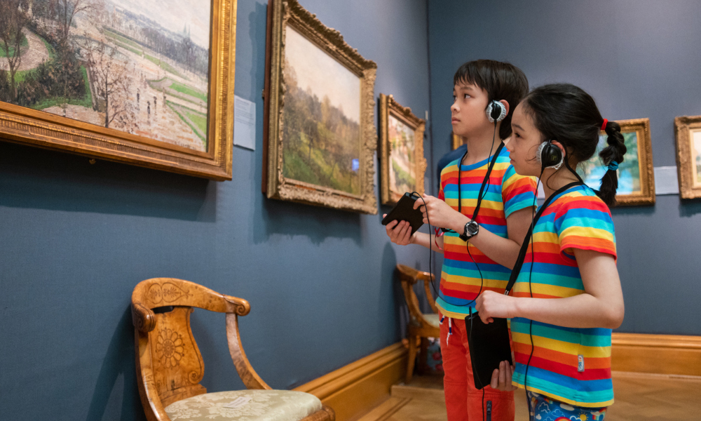 Children use tablets and headphones inside a gallery