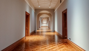 A photograph of a long hallway with an intricate wood floor