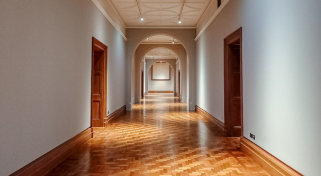 A photograph of a long hallway with an intricate wood floor