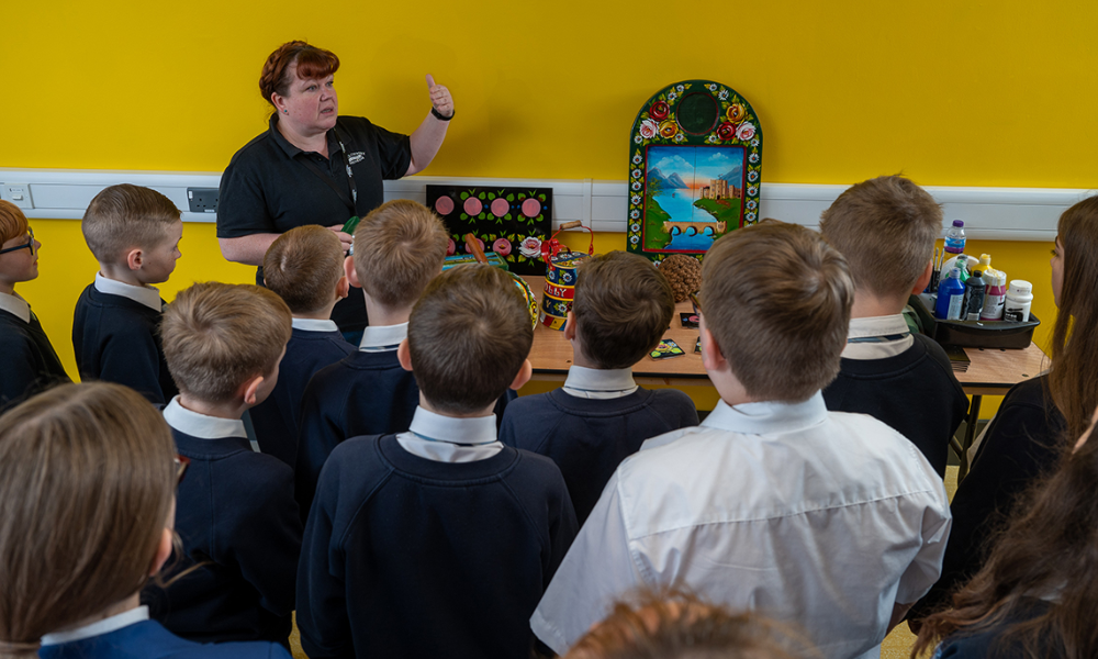 BCLM Tutor and heritage craft specialist Kerri shows the pupils of Bramford Primary School examples of traditional canal art in the Weston Room of the new facility.